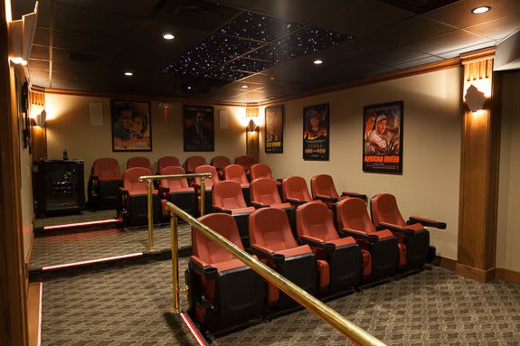 A cozy home theater with multiple rows of seats and classic movie posters on the walls.