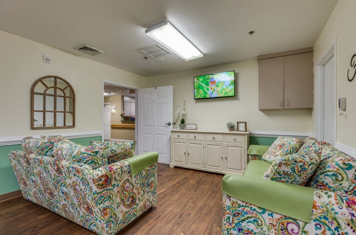 A cozy waiting room with patterned sofas and a television on the wall.