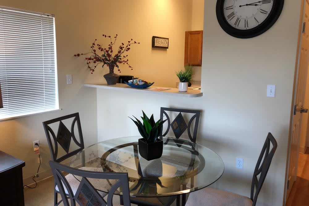 A cozy dining area with a glass table and decorative plants.