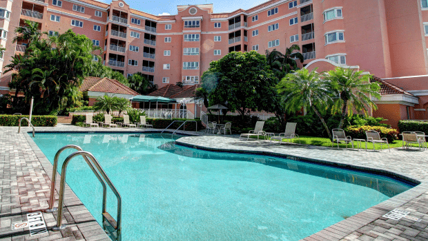 A luxury hotel with a large swimming pool surrounded by lush greenery.