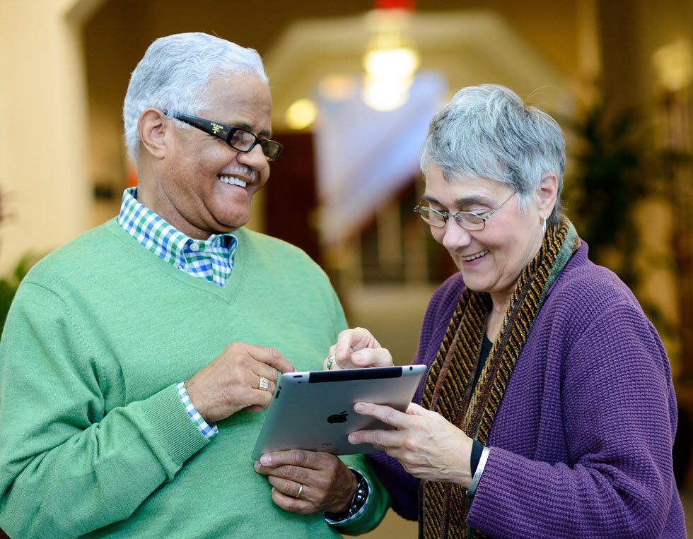 Two seniors happily using a tablet together.