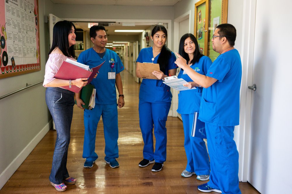 A group of healthcare professionals having a discussion in a hospital corridor.