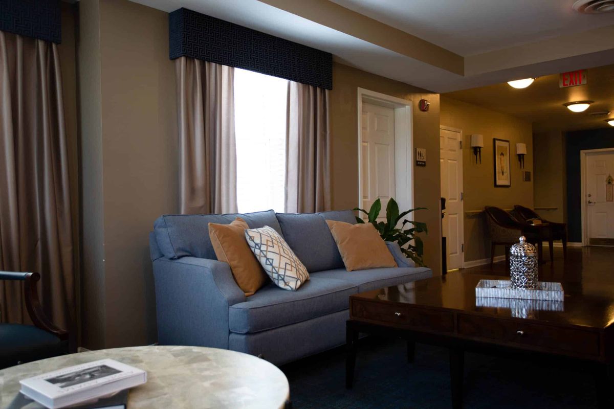 A cozy living room with a blue sofa, decorative pillows, and a coffee table by a window.