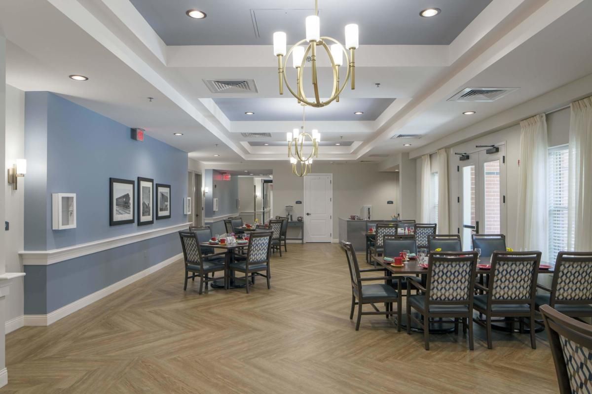 A modern dining room with elegant chandeliers and neatly arranged tables and chairs.