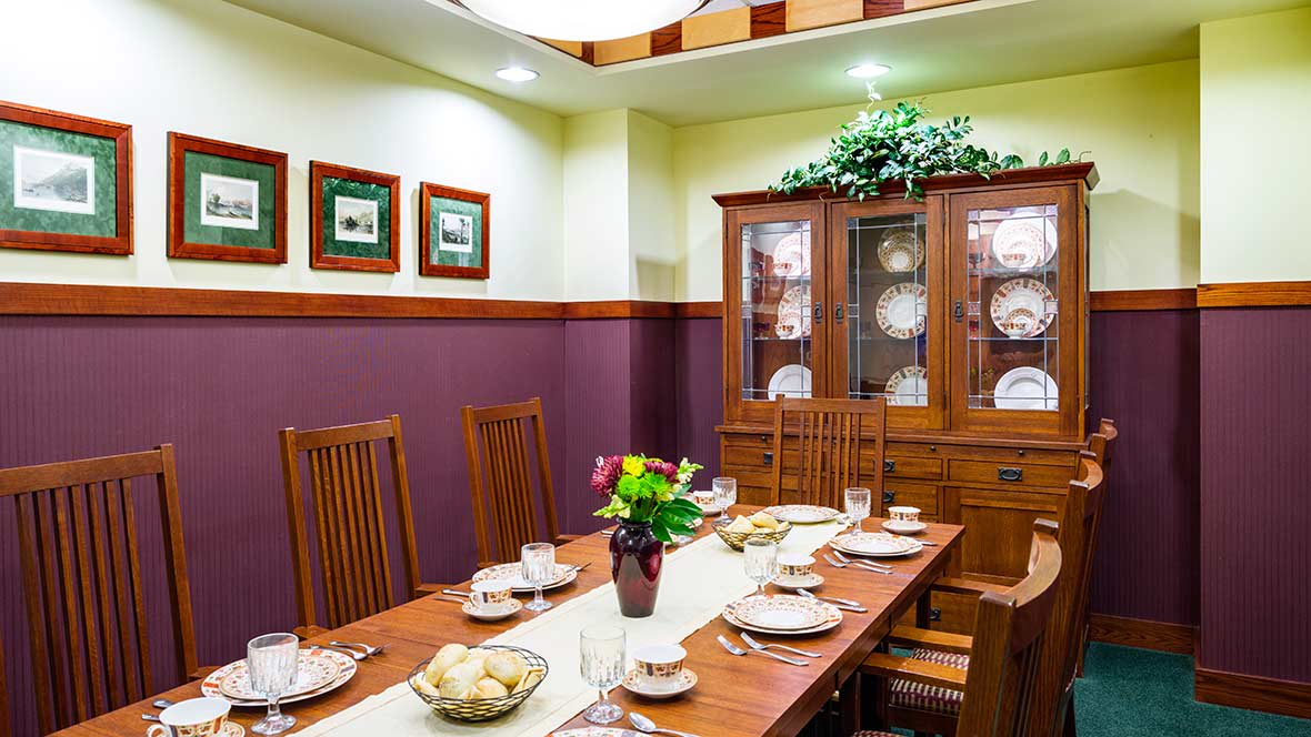 A beautifully arranged dining room with a wooden table set for a meal, complete with a china cabinet and decorative elements.