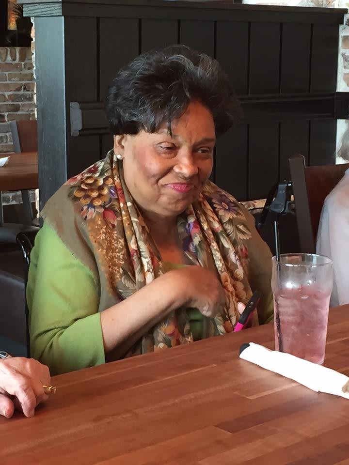 A woman sitting at a restaurant table with a drink.