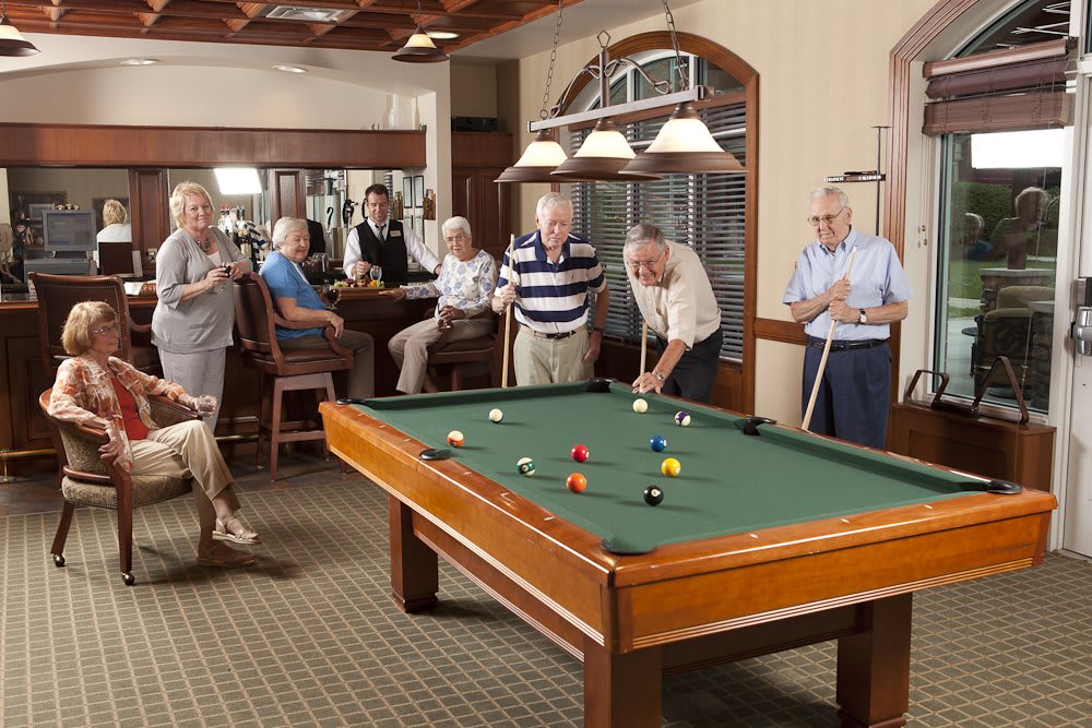 A group of senior citizens enjoying a game of billiards in an indoor recreational area.