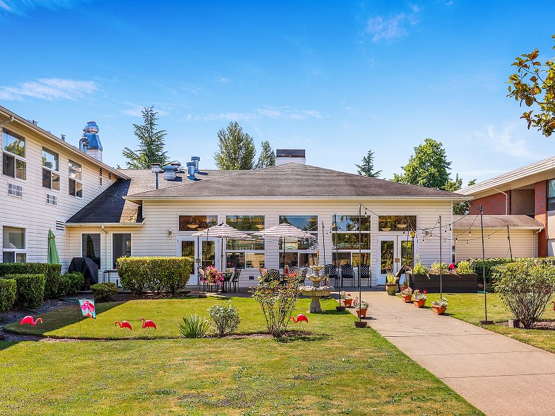A beautiful house with a well-maintained garden and patio on a sunny day.