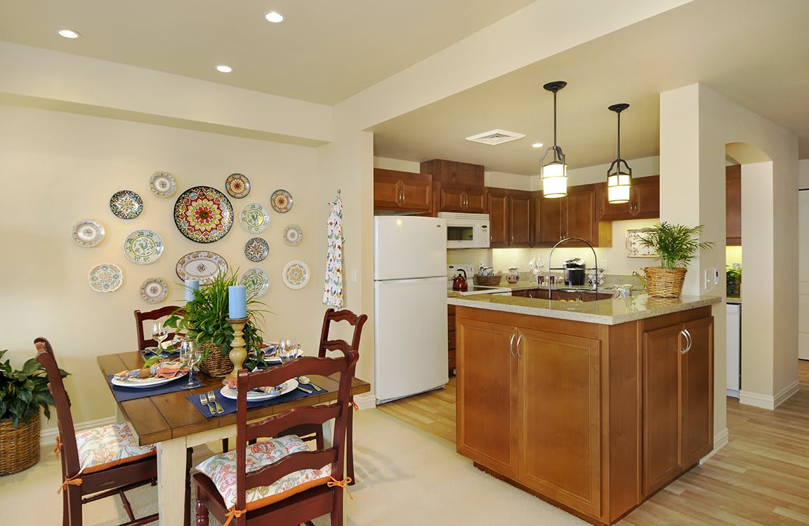 A cozy kitchen and dining area featuring wooden cabinets and decoratively arranged plates on the wall.