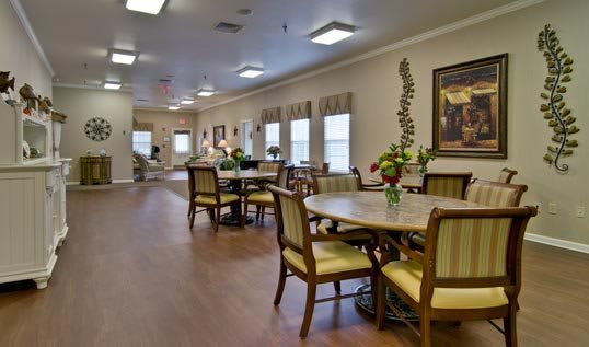 A well-lit dining area featuring multiple tables and chairs, adorned with decorative plants.