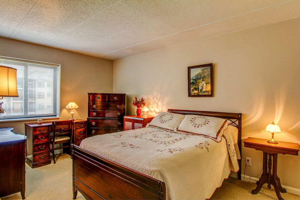 A cozy bedroom with a wooden bed, desk, and soft lighting.