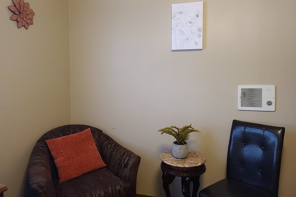 A cozy waiting area with a chair, side table, and potted plant.