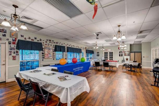A decorated event space with tables and colorful balloons set up for a gathering.
