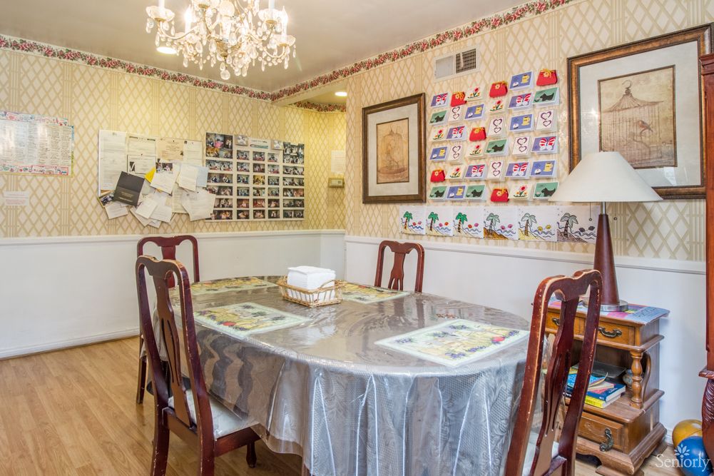 A cozy dining room with a chandelier and wall decorations.