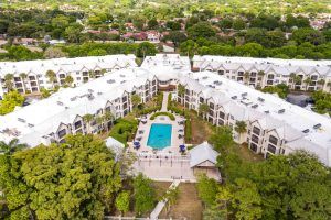 Aerial view of a resort with a central swimming pool surrounded by buildings and greenery.