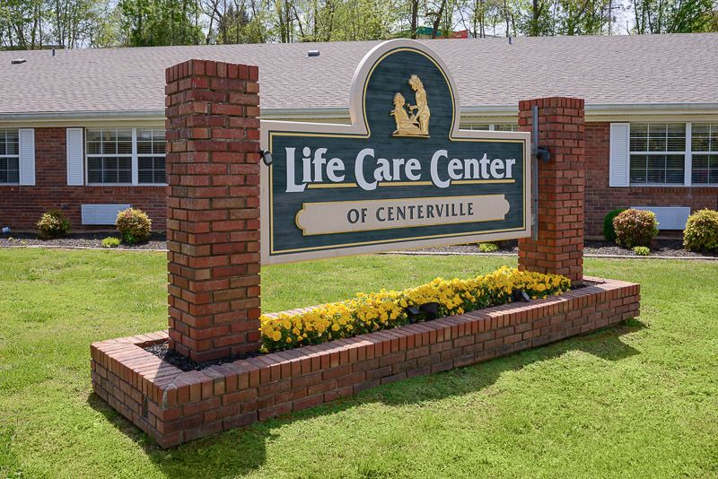 A sign for the Life Care Center of Centerville displayed in front of a brick structure with surrounding greenery.