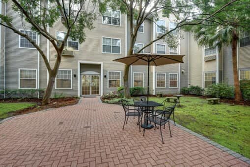 A peaceful courtyard with patio furniture and an umbrella surrounded by apartment buildings.