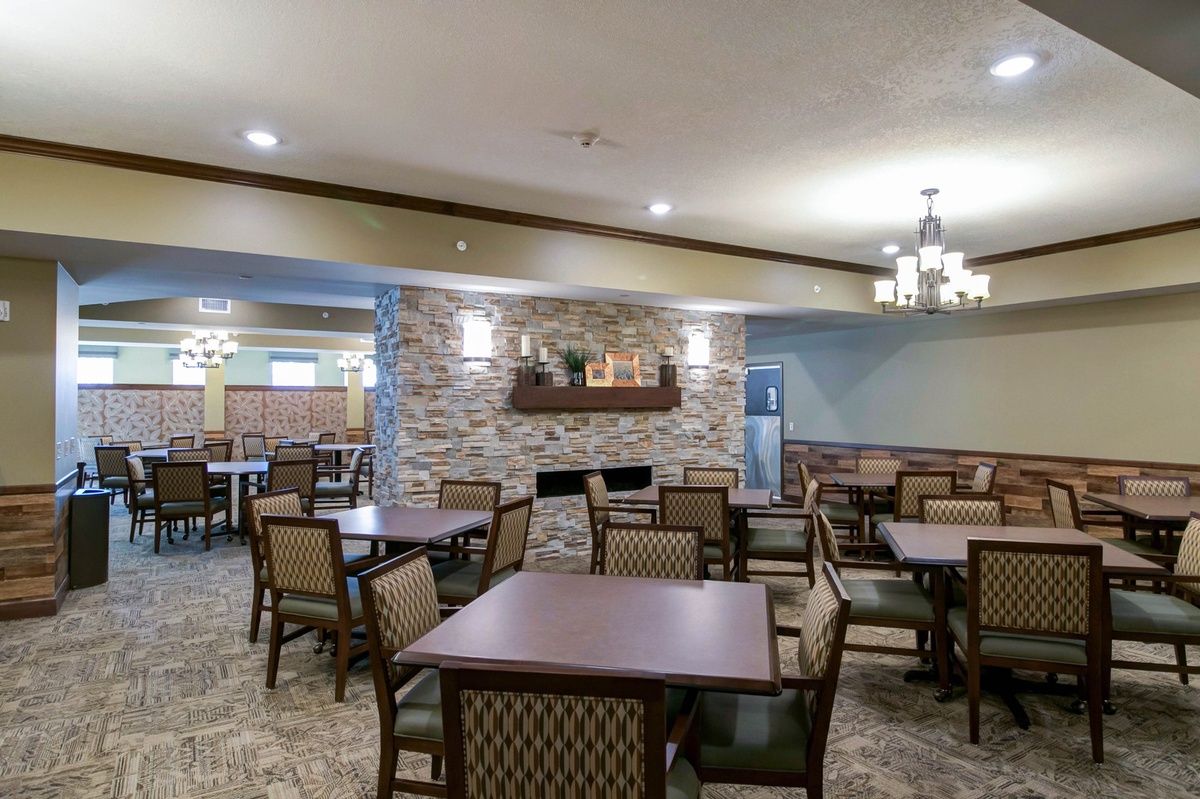A cozy dining area with neatly arranged tables and chairs, complemented by warm indoor lighting.