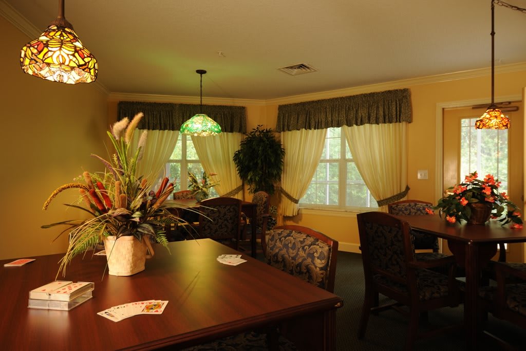 A cozy dining room with a wooden table, chairs, and large windows adorned with curtains.