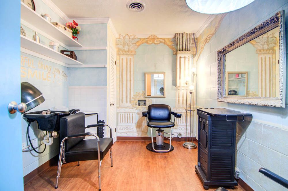 A cozy hair salon interior with styling chairs, a mirror, and decorative elements.
