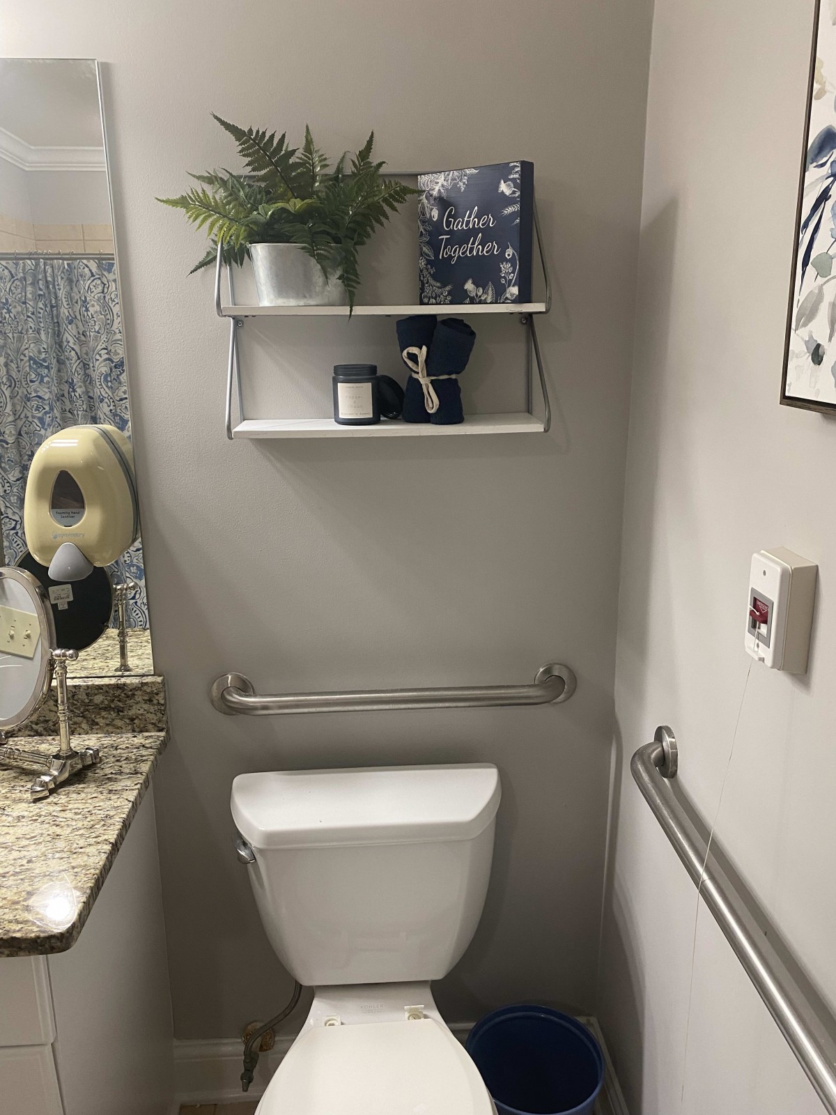 A neatly organized bathroom with a toilet, shelves holding decor items, and a mirror.