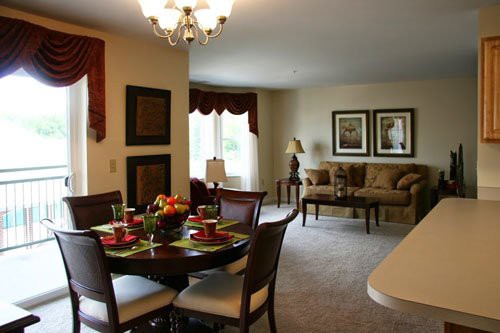 A beautifully decorated dining and living area with a dining table set, chandelier, and cozy seating.