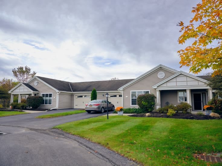 A suburban house with a well-kept lawn and driveway under an overcast sky.