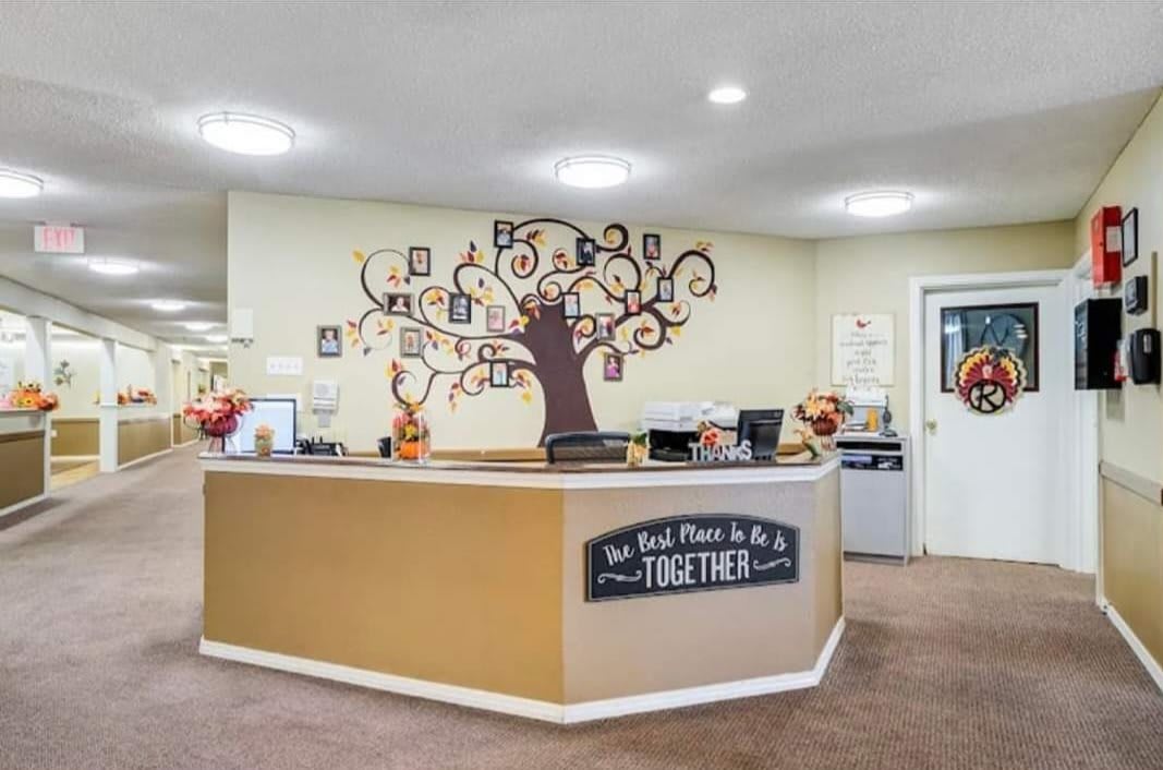 A welcoming reception area with a decorative tree mural on the wall behind the counter.