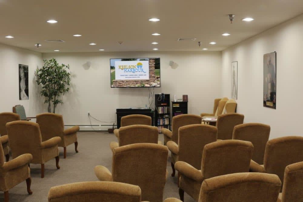 A conference room with arranged seating facing a television for presentations.