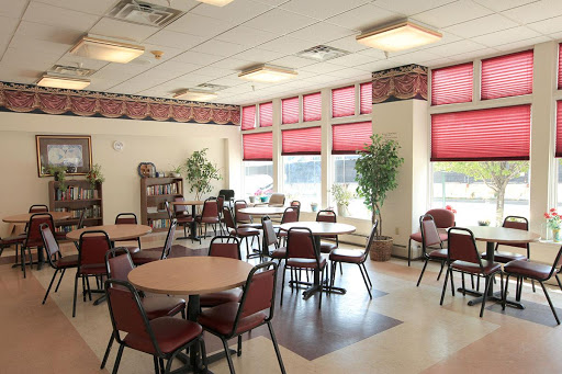 A bright and inviting dining area featuring tables and chairs, adorned with red blinds and potted plants.