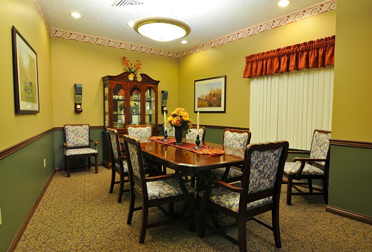 A well-decorated dining room featuring a large table with chairs, a cabinet, and warm lighting.