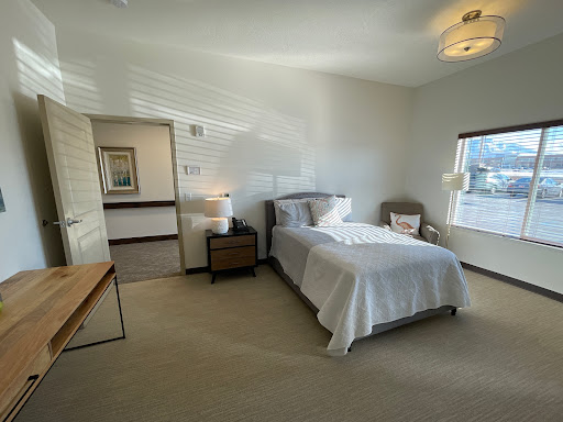 A bright and minimalistic bedroom featuring a single bed, nightstand, and natural lighting.
