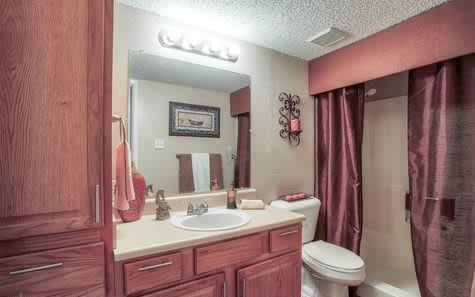A cozy bathroom with wooden cabinets, a mirror, and a shower area.