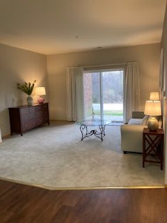 A cozy living room with elegant decor, featuring a sofa, coffee table, and multiple lamps, with a view through sliding glass doors.