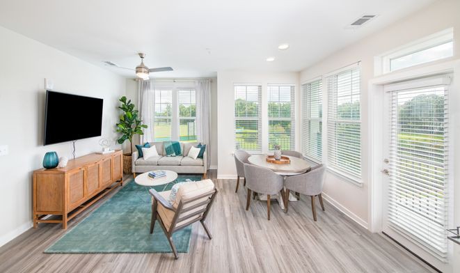 A modern, bright living room and dining area with large windows and stylish decor.