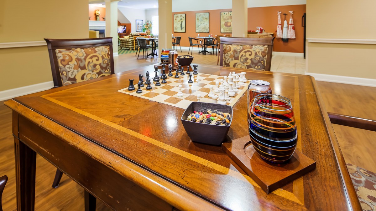 A cozy game room with a chessboard set up on a wooden table, surrounded by comfortable seating.