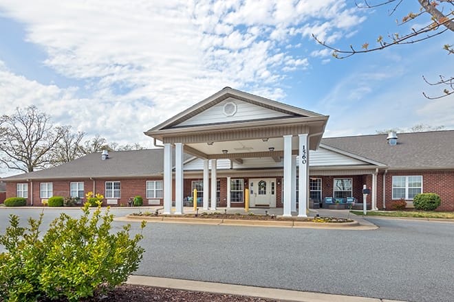 A building with a prominent entrance featuring columns under a partly cloudy sky.