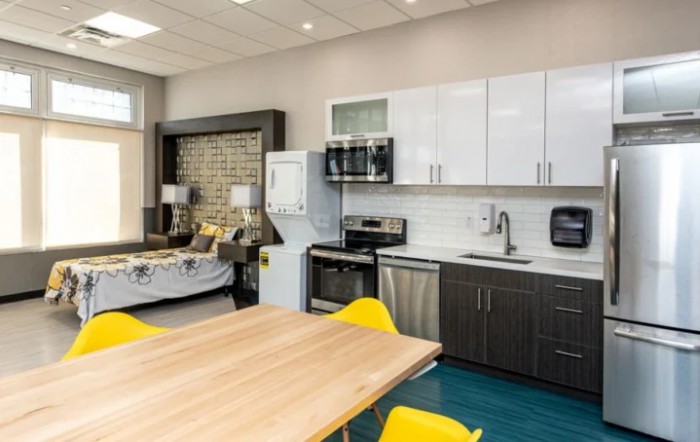 A modern open-concept kitchen and living area with a dining table and yellow chairs.