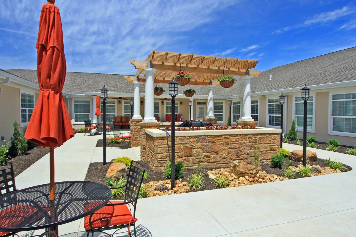 A beautifully landscaped courtyard featuring a pergola, outdoor seating, and vibrant garden elements.