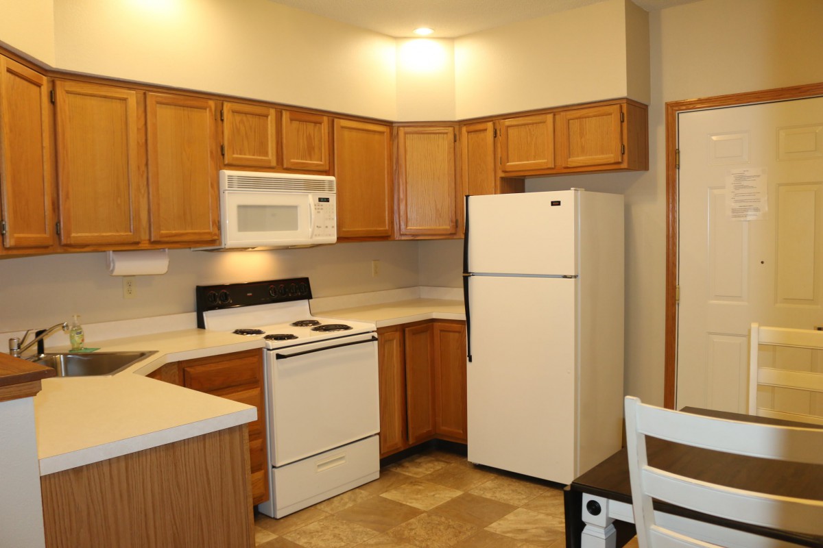 A modern kitchen with wooden cabinets and essential appliances.