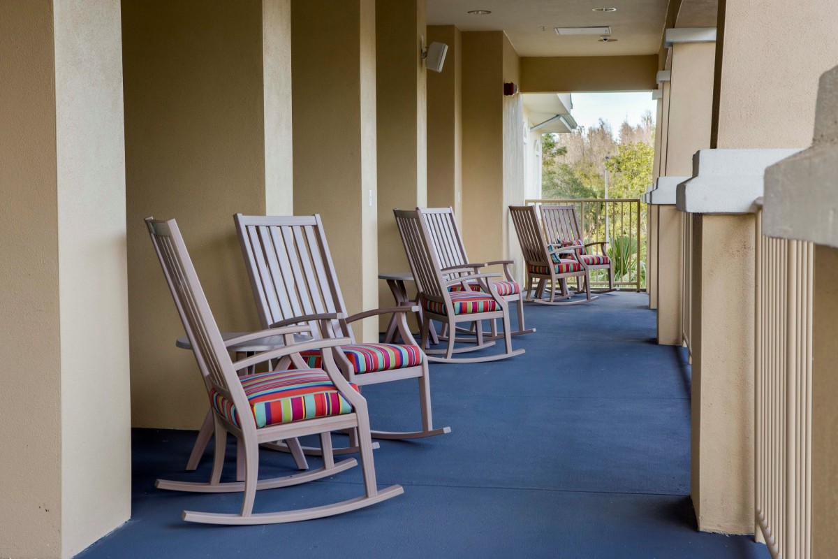 A row of rocking chairs lined up on a balcony.