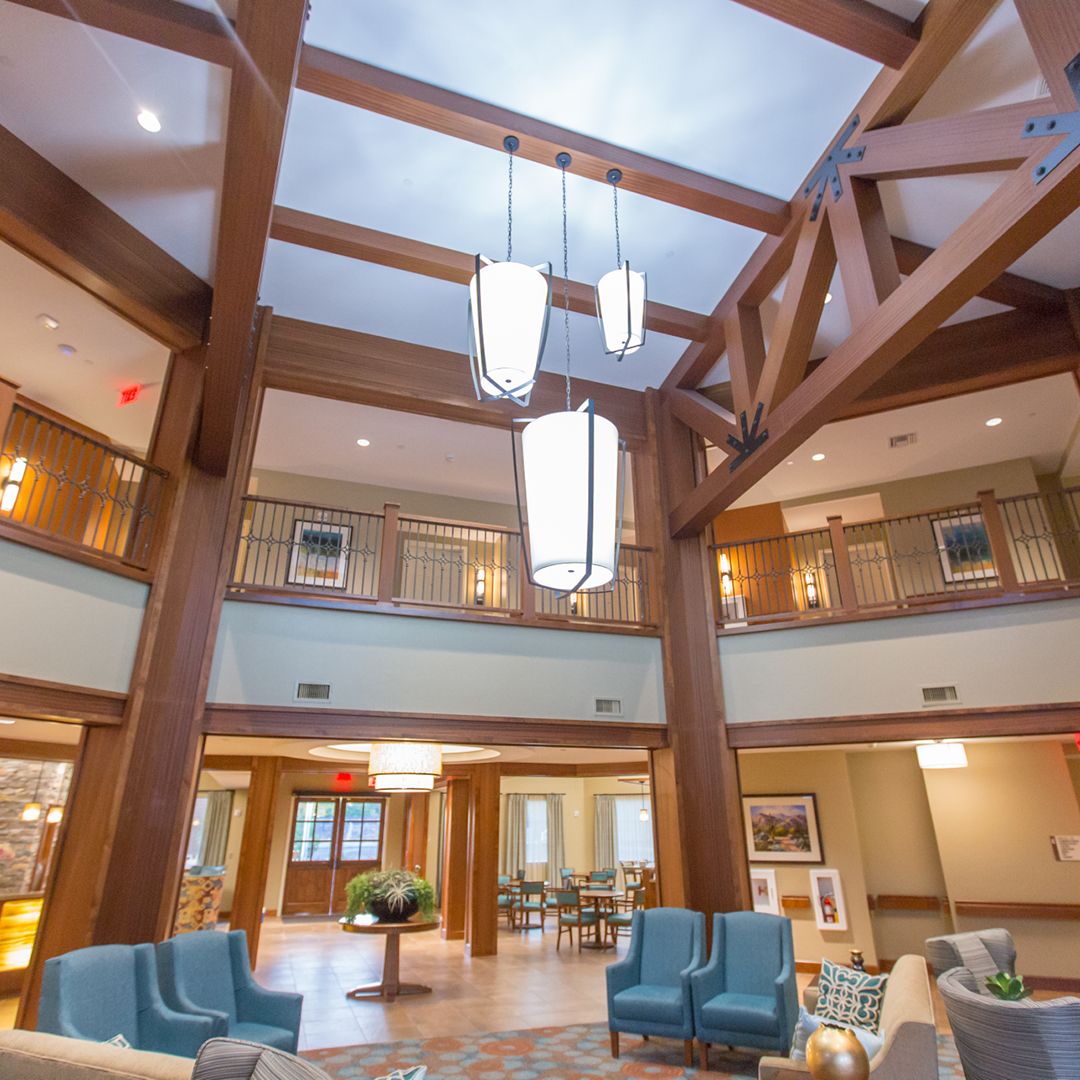 A spacious and elegant lobby featuring wooden beams, modern chandeliers, and comfortable seating.