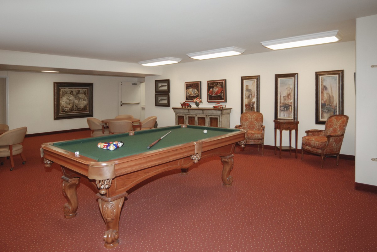 A cozy billiards room with a pool table and comfortable seating.