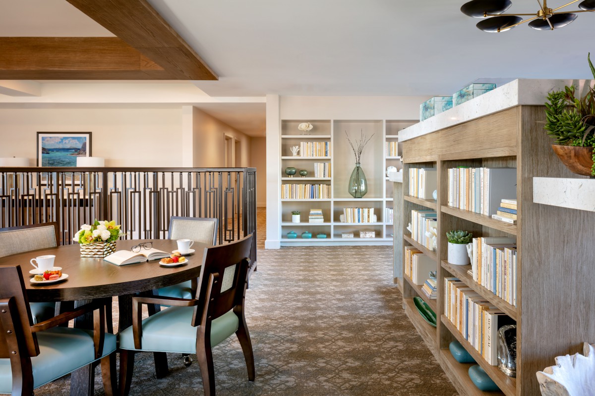 A modern open-plan living area with stylish bookshelves and a cozy dining table.