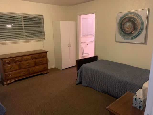 A simple bedroom with a single bed, dresser, and wardrobe.
