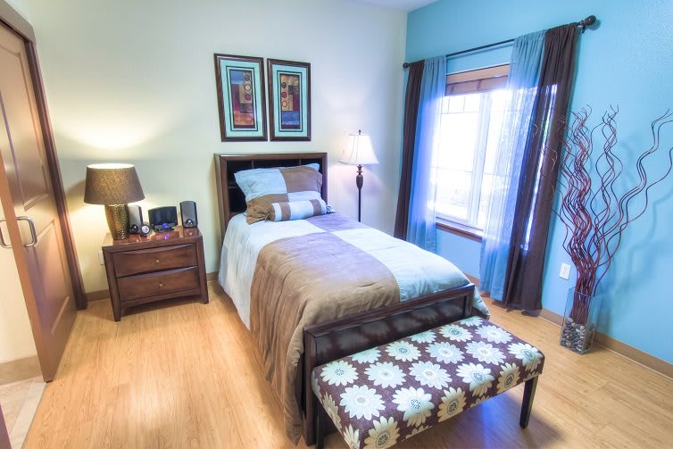 A neatly decorated bedroom featuring a single bed, nightstand, and framed artwork.