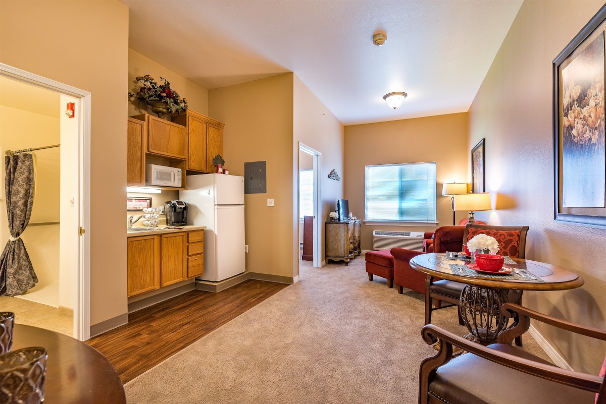 A cozy apartment living room with a kitchenette and comfortable seating.