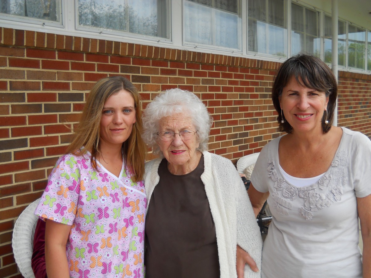 Three women posing together outside in front of a brick building.