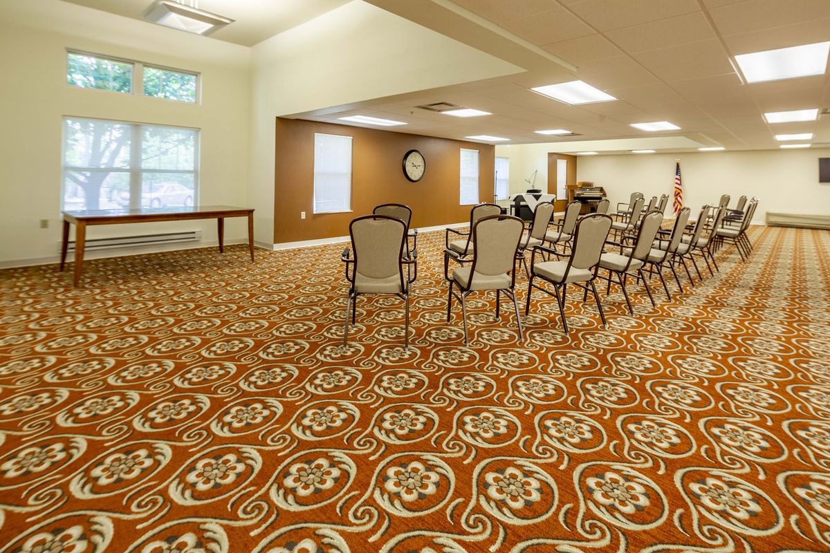 An empty conference room with patterned carpeting and arranged chairs.
