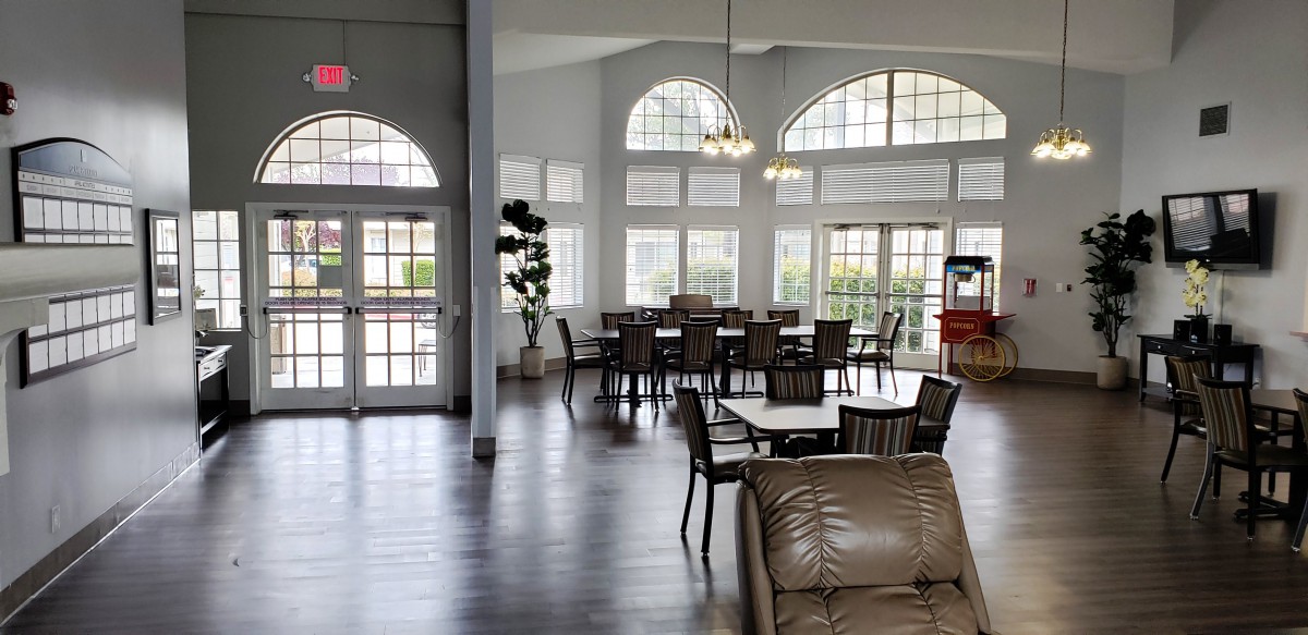 A spacious and well-lit lobby area with tables, chairs, and large windows.